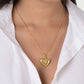An 18K gold plated brass Heart Radiant Charm hangs from a delicate gold chain worn around a person’s neck.
