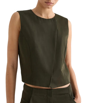 A person wearing the TWP High Neck Hidden Placket Vest in dark olive green with matching pants stands against a plain light background.