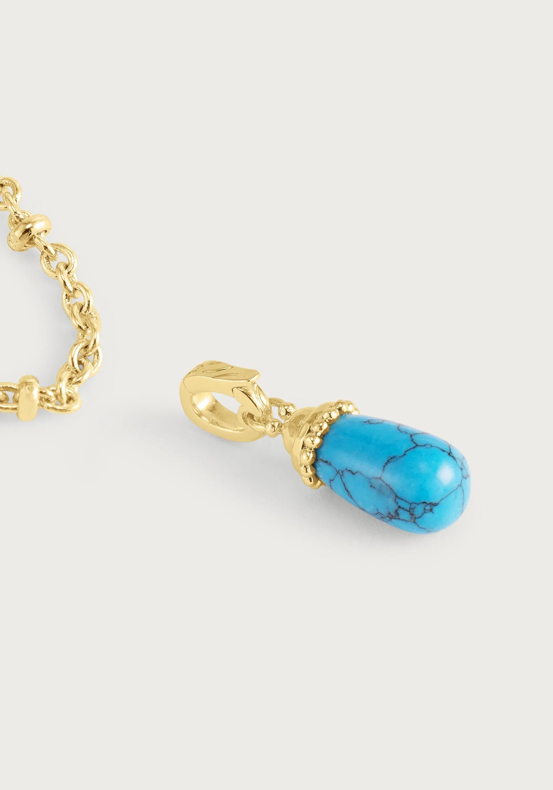 The Anabel Aram Milos Stone Drop Charm features a detachable teardrop-shaped turquoise stone with intricate gold detailing, perfect for adding to your favorite gold chain necklace.