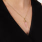 A person wearing the Anabel Aram Milos Stone Horn Charm gold chain necklace with a Mediterranean pink horn pendant, paired with a black V-neck top.