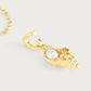 Anabel Aram Milos Shell with Pearl Charm, a gold shell-shaped pendant with a central pearl attached to a gold hoop earring.