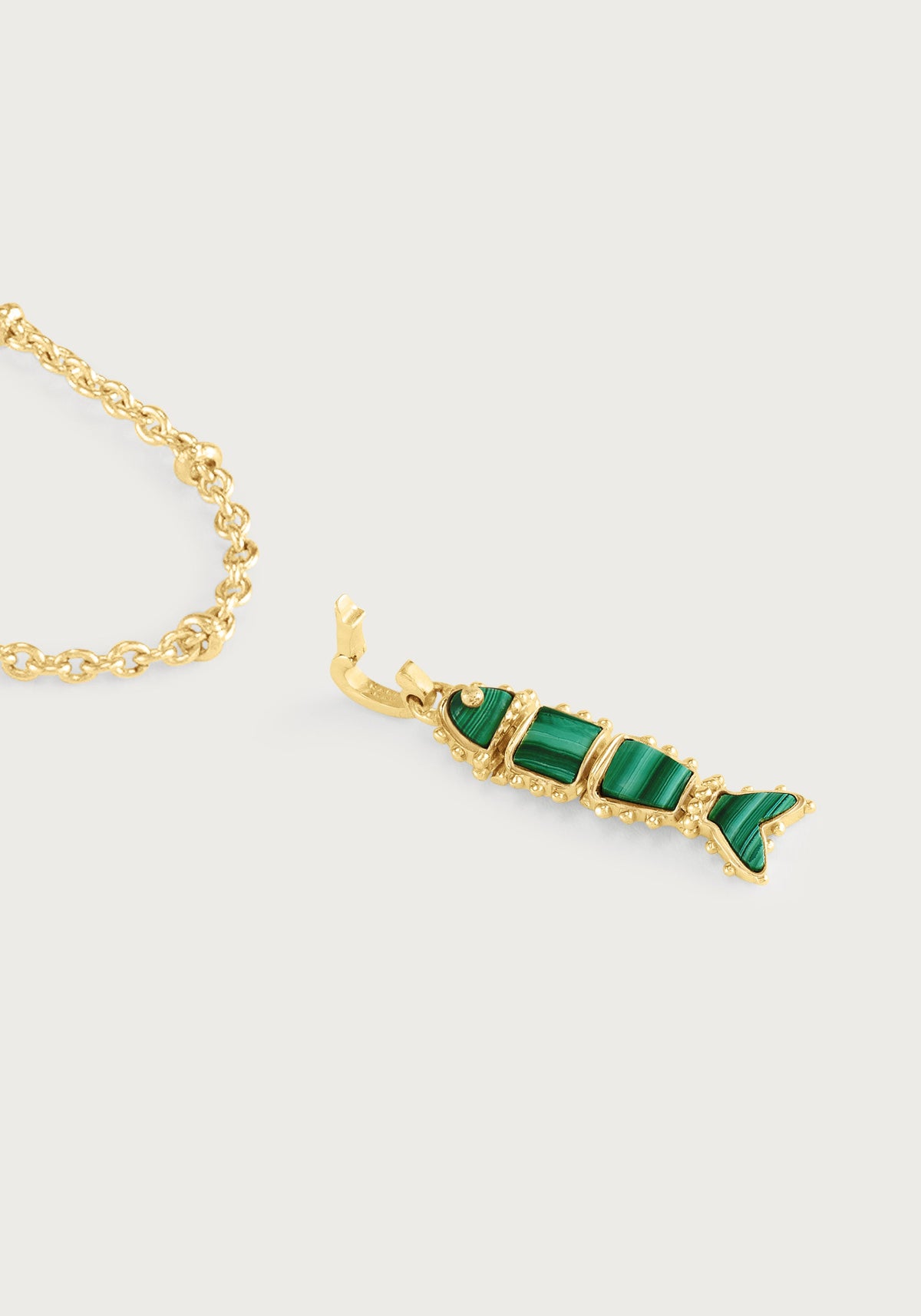 Milos Stone Fish Charm in the shape of a gold fish with green stone segments, detached from a gold chain.