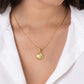 A woman wears a white blouse and the Anabel Aram Scallop Shell Charm, an 18k gold plated necklace.