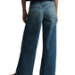 A person is seen from behind wearing TWP's Tiny Dancer Jeans, vintage-inspired wide-leg denim, paired with beige shoes.