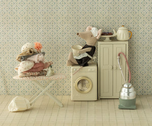 Maid Mouse, Big Sister by Maileg features a whimsical laundry room scene with toy mice, an ironing board and folded clothes, kitchen utensils, washing machine, cabinets, vacuum cleaner, teapot, and patterned wallpaper.