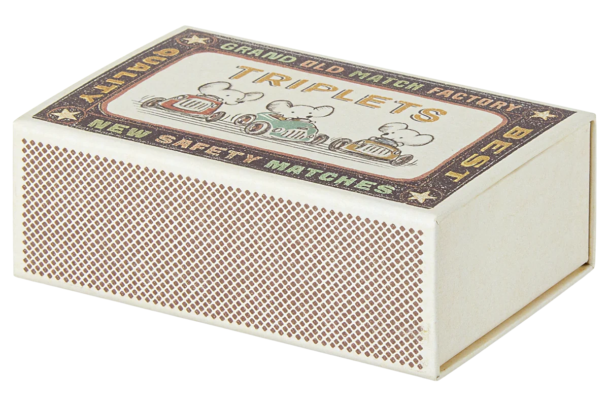 The Maileg Baby Triplets in Box features a rectangular box with a vintage "Triplets" label, Grand Old Match Factory branding, cartoon cars, cozy space for baby mice inside, and brown match striking surfaces on the sides.