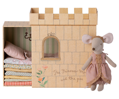 A Maileg Princess and the Pea Mouse dressed as a princess standing beside a cardboard castle playset with a stack of patterned mattresses inside, inspired by the fairy tale "The Princess and the Pea.