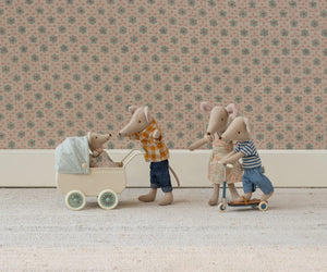 Maileg’s Mum Mouse pushes a pram with baby while another rides a scooter with two mouse dolls, all set against floral wallpaper—charming Maileg mice that pair perfectly with delightful furniture accessories.