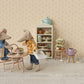 Maileg’s Dad Mouse enjoys tea and pastries at a small table with mouse furniture, surrounded by shelves of baked goods and baking supplies in a cozy miniature kitchen scene.
