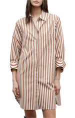A woman wears the TWP Morning After Dress, featuring brown and white vertical stripes, long sleeves, a chest pocket, and a relaxed silhouette.
