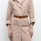 A woman wears the TWP Morning After Dress—brown and white vertical stripes, relaxed fit, brown belt, and rolled-up sleeves—standing against a plain white background.