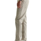 A person in AG Jeans' Tellis Commuter Performance Airluxe Modern Slim pants (beige, tapered), a green shirt, white sneakers, and a watch stands with their left side facing the camera.
