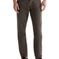 A person wears AG Jeans' Tellis Modern Slim Denim in brown, styled with a white shirt and brown loafers, standing against a plain background.