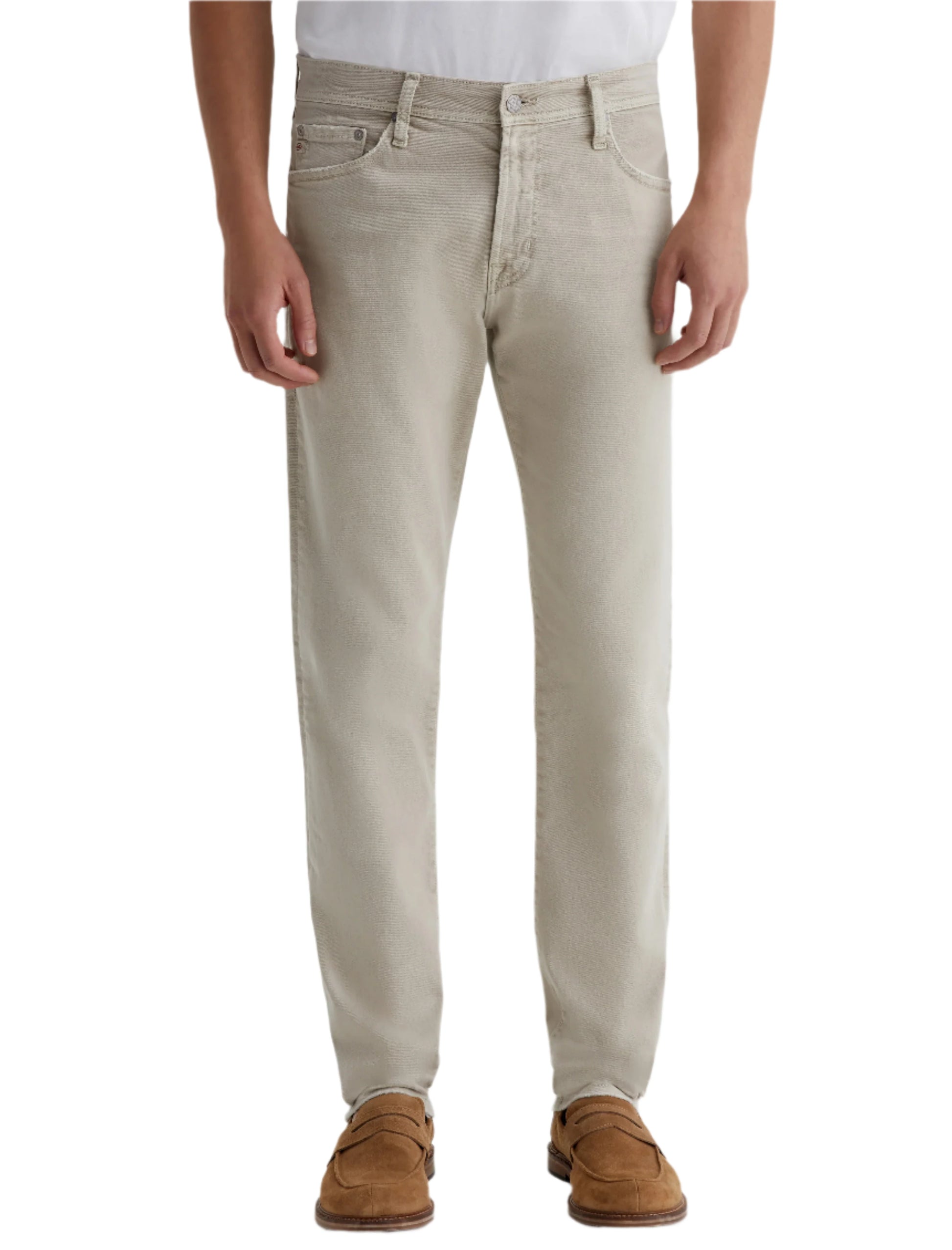 A person wearing AG Jeans Tellis AG-ed™ Modern Slim Denim in light beige, paired with a white shirt and brown suede shoes, is shown from shoulders to feet against a plain background.