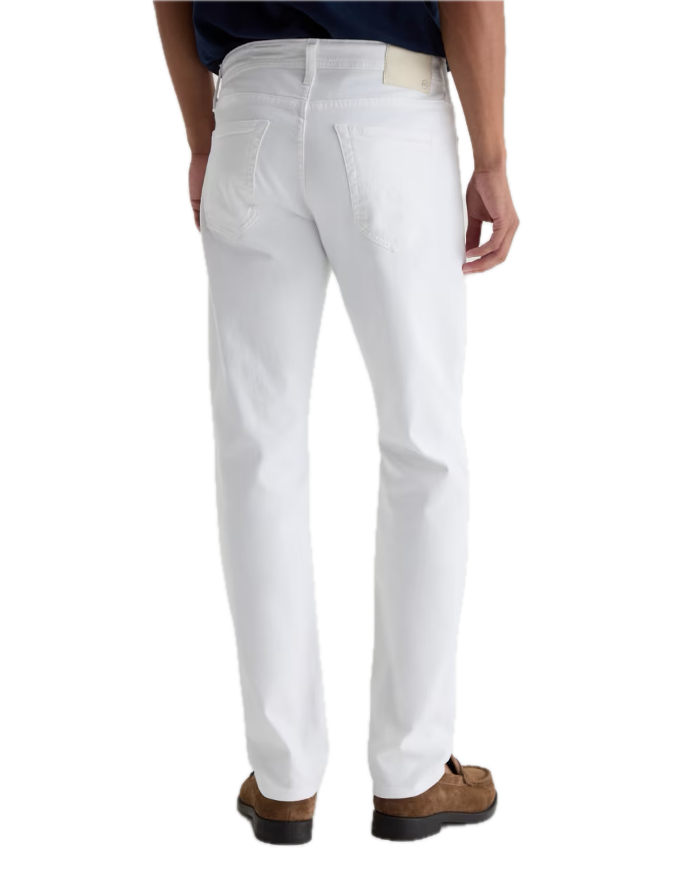 A person stands facing away, wearing AG Jeans’ Tellis Cloud Soft Denim™ white slim fit men’s jeans, styled with a navy shirt and brown suede shoes against a white background.