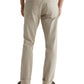 A person wearing AG Jeans Tellis Selvage khaki men's jeans, a white shirt, and dark sneakers stands with their back to the camera.