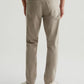 A person is shown from the back against a plain light background, wearing AG Jeans Tellis Sueded Sateen Jeans in beige paired with white sneakers.