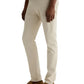 A person wearing light beige Tellis Modern Slim Sueded Stretch Sateen pants from AG Jeans, a light grey shirt, and brown suede loafers stands against a plain light background.
