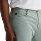 A person wearing AG Jeans Everett Slim Straight Leg cotton-linen twill men's pants in light green and a white shirt, with their left hand resting by their side.