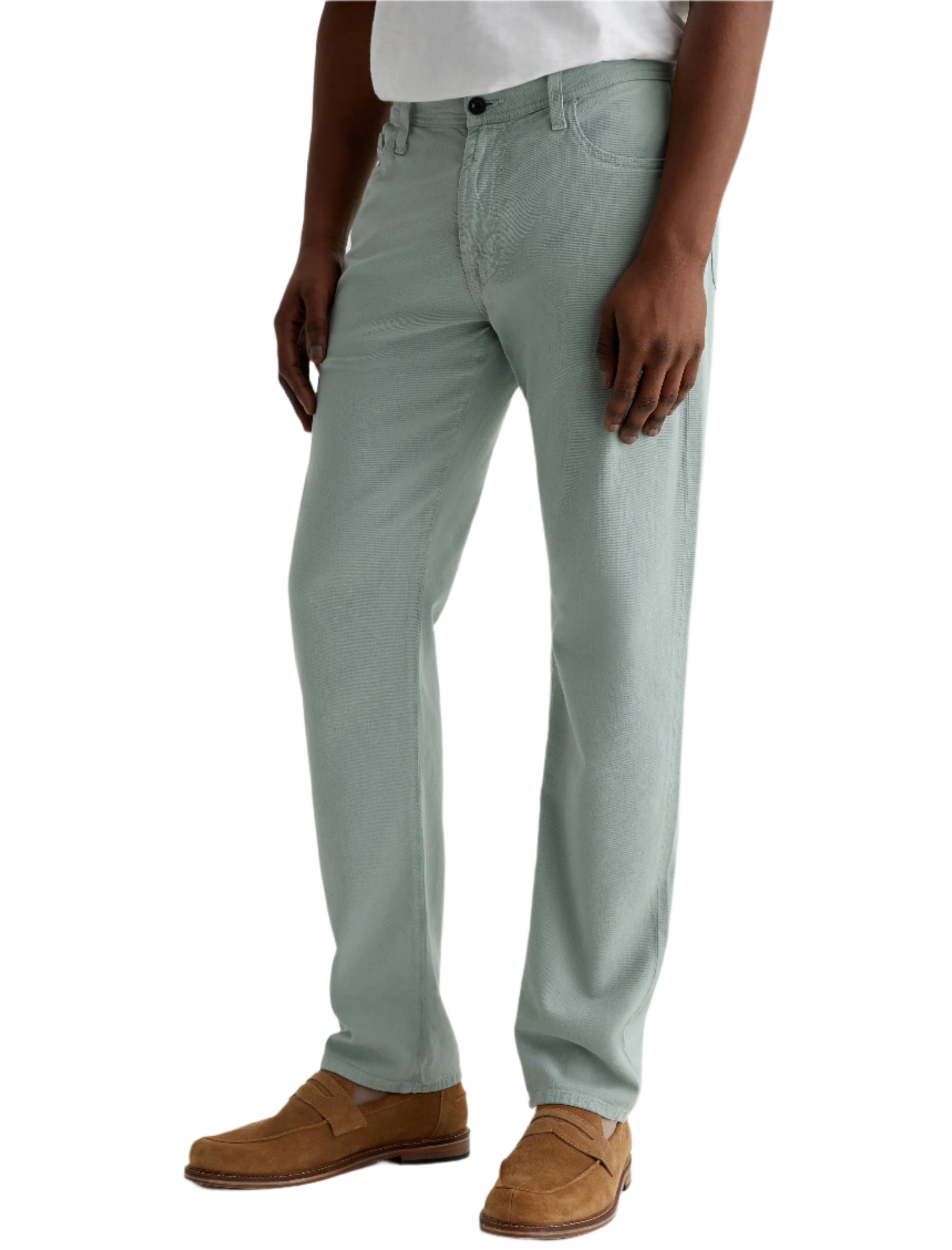 A person wearing AG Jeans Everett Slim Straight Leg men's pants in light green with a white shirt and tan suede loafers, standing against a white background.