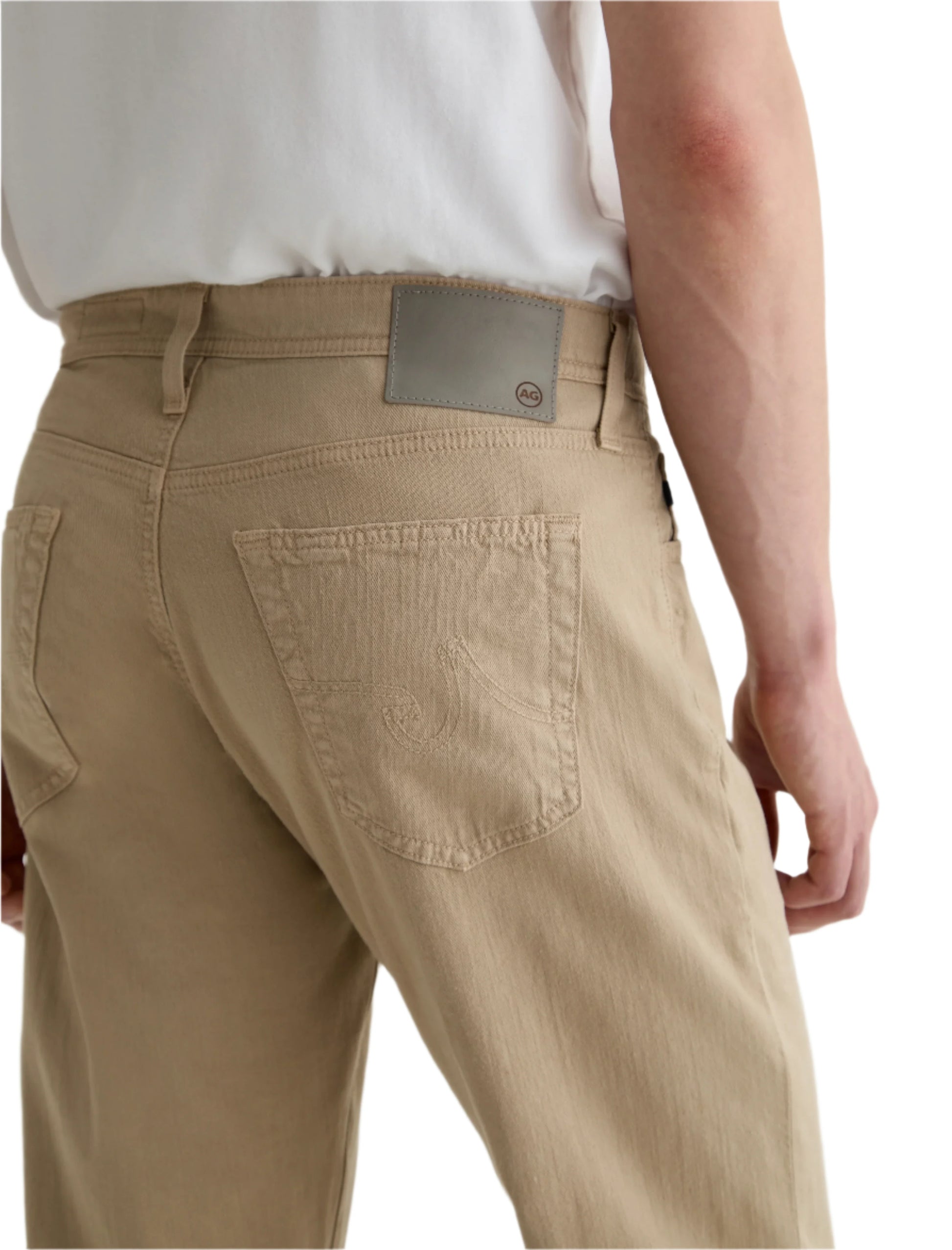 A person shown from the back wears AG Jeans' Everett Slim Straight jeans in beige with a white shirt, highlighting the mid-rise waist and detailed pockets.