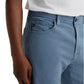 A person wearing AG Jeans' Everett Slim Straight jeans in a light blue wash with a mid-rise waist and five-pocket design, paired with a white shirt, shown from mid-torso to knee, one hand resting by their side.