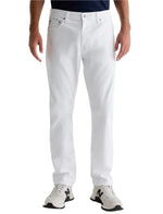 A person wears AG Jeans Everett Sueded Slim Straight white jeans and white sneakers, standing against a plain background, shown from torso to feet.