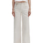 A person wears TWP Tiny Dancer Jeans—high-waisted, vintage-inspired wide-leg denim—with a cropped white shirt and white shoes, standing against a plain white background.