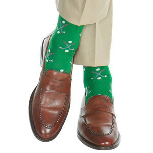Person in tan pants and brown loafers wears Dapper Classics Green with Steel Gray and Ash/White Golf Club and Ball Cotton Sock—mid-calf dress socks featuring a crossed golf club and ball pattern.