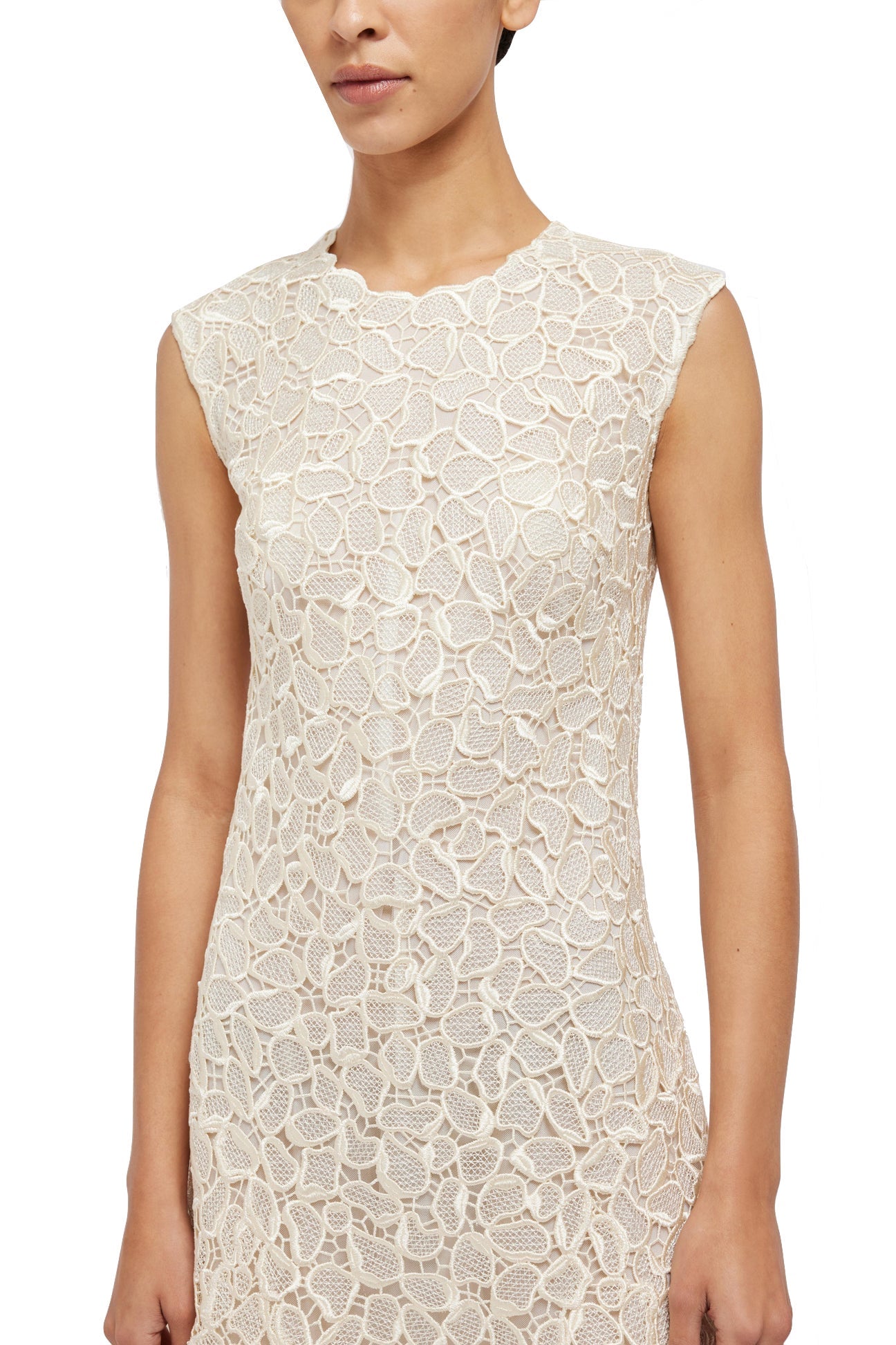 A person wearing a sleeveless, cream-colored Simkhai Drake Mini Dress with a floral pattern against a white background, showcasing the timeless craftsmanship of Simkhai and an elevated everyday elegance.