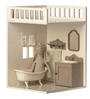 A Maileg stuffed rabbit is in the House of Miniature Bathroom by Maileg, with sink, mirror, towel, and lace curtain furniture pieces on a white and beige background.