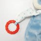 The Skipit's Activity Toy by Bunnies By the Bay features a soft design with blue fabric, a polka-dotted white cloth arm, and a red teething ring against a white background to provide teether options for sensory development.
