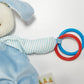 Skipit's Activity Toy by Bunnies By the Bay is designed for sensory development, featuring red and blue rings in a striped sleeve and a carrot-themed tag. It's an engaging toy perfect for little explorers.