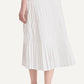 A person is seen from the back wearing the Merlette New York Litus Skirt—a white pleated midi that brings graceful movement and elegance—paired with black sandals against a plain background.