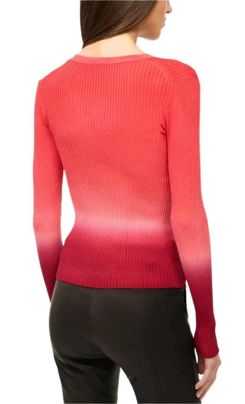 A person dressed in the Staud Cargo Sweater, featuring a red ribbed knit with a dip-dye print that fades to white at the bottom, paired with black pants, facing away.