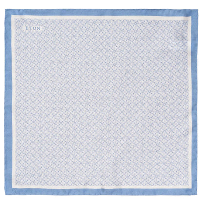 A light blue geometric silk pocket square by Eton with a subtle floral pattern and "ETON" in the corner.