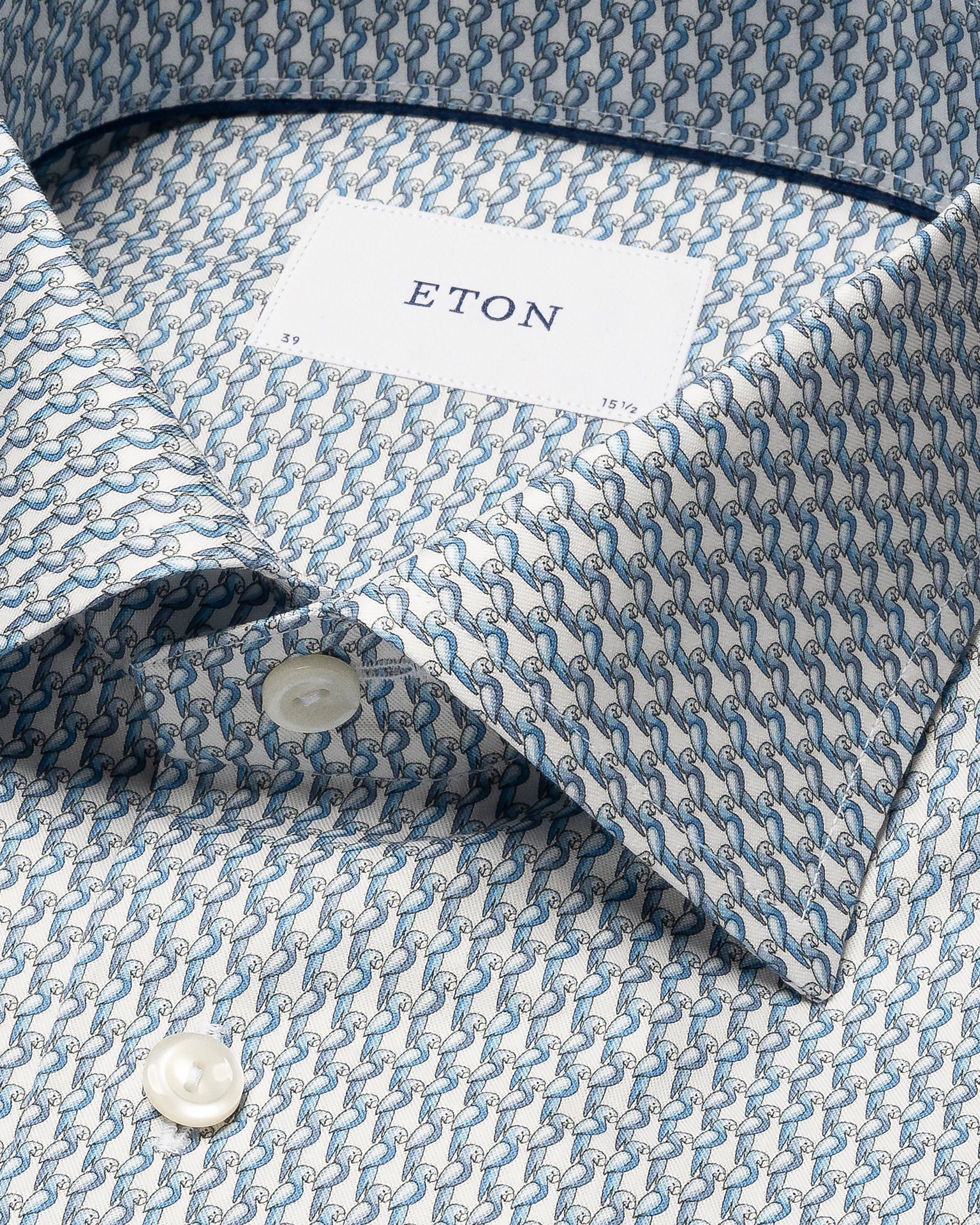 Close-up of the Cut Away Slim Signature Twill Parrot Shirt by Eton, featuring neatly folded blue and white interlocking chain patterns. Fabric ensures a wrinkle-free finish with visible buttons at the collar.