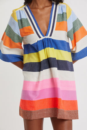 Wearing the Lemlem Belkis Caftan—a short, hand-woven multicolored dress with a deep V-neck and wide sleeves—brings effortless bohemian flair.