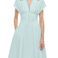 A woman wears the Simkhai Farlow Dress—a polished, light blue cotton faille midi with short sleeves, pleats, and a front zipper.