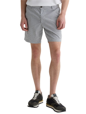 A person wears AG Jeans Cipher Short in black and white with a mid-rise waist, paired with a crisp white shirt and black sneakers, standing against a plain white background.