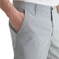 A person wearing a white shirt and AG Jeans Cipher Short blue-and-white striped pants with a mid-rise waist stands with one hand in their pocket.