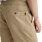 A person wearing the AG Jeans Oliver Short in breathable twill with a back pocket and adjustable drawstring waist, styled with a white shirt, shown from the waist down at an angle.