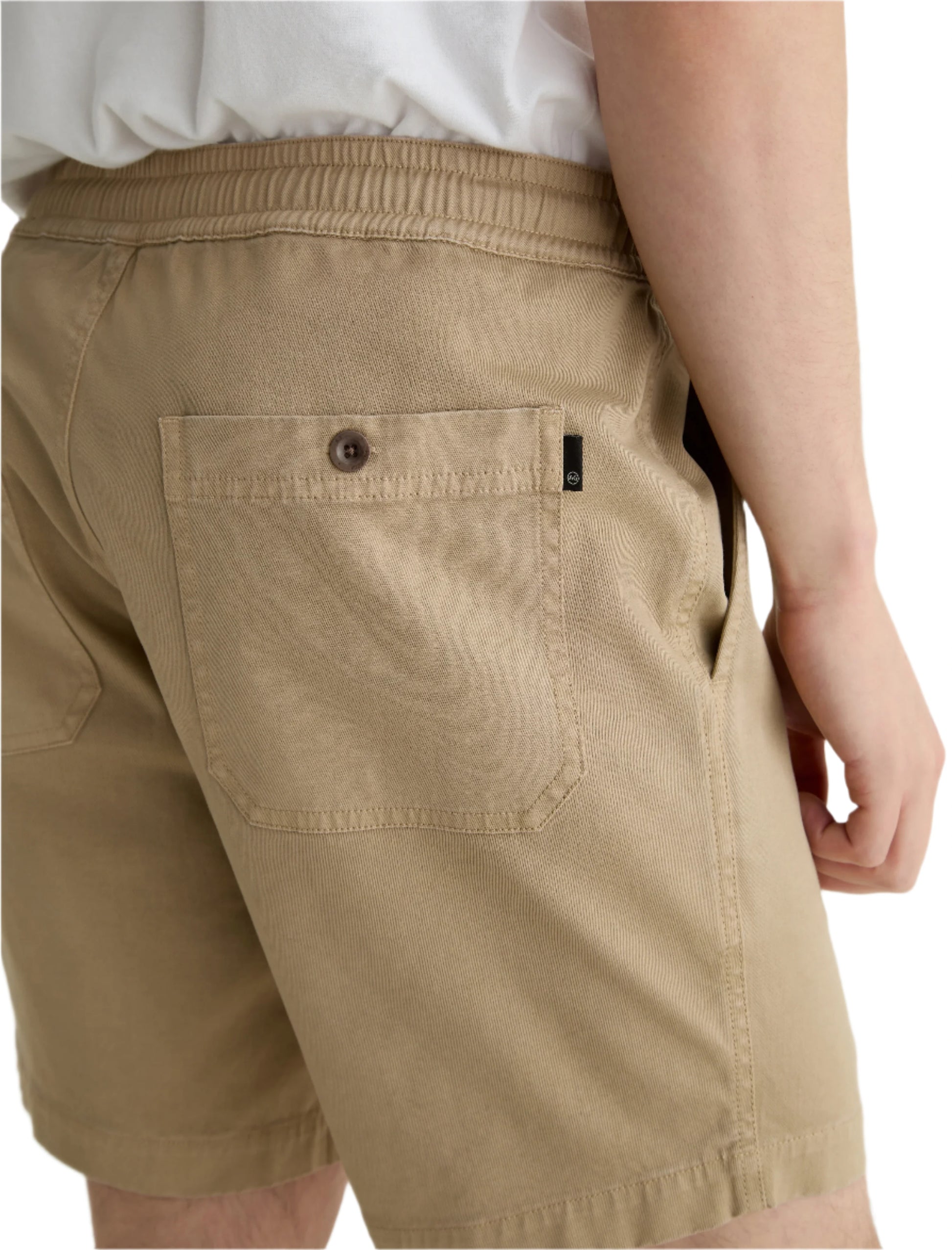 A person wearing the AG Jeans Oliver Short in breathable twill with a back pocket and adjustable drawstring waist, styled with a white shirt, shown from the waist down at an angle.
