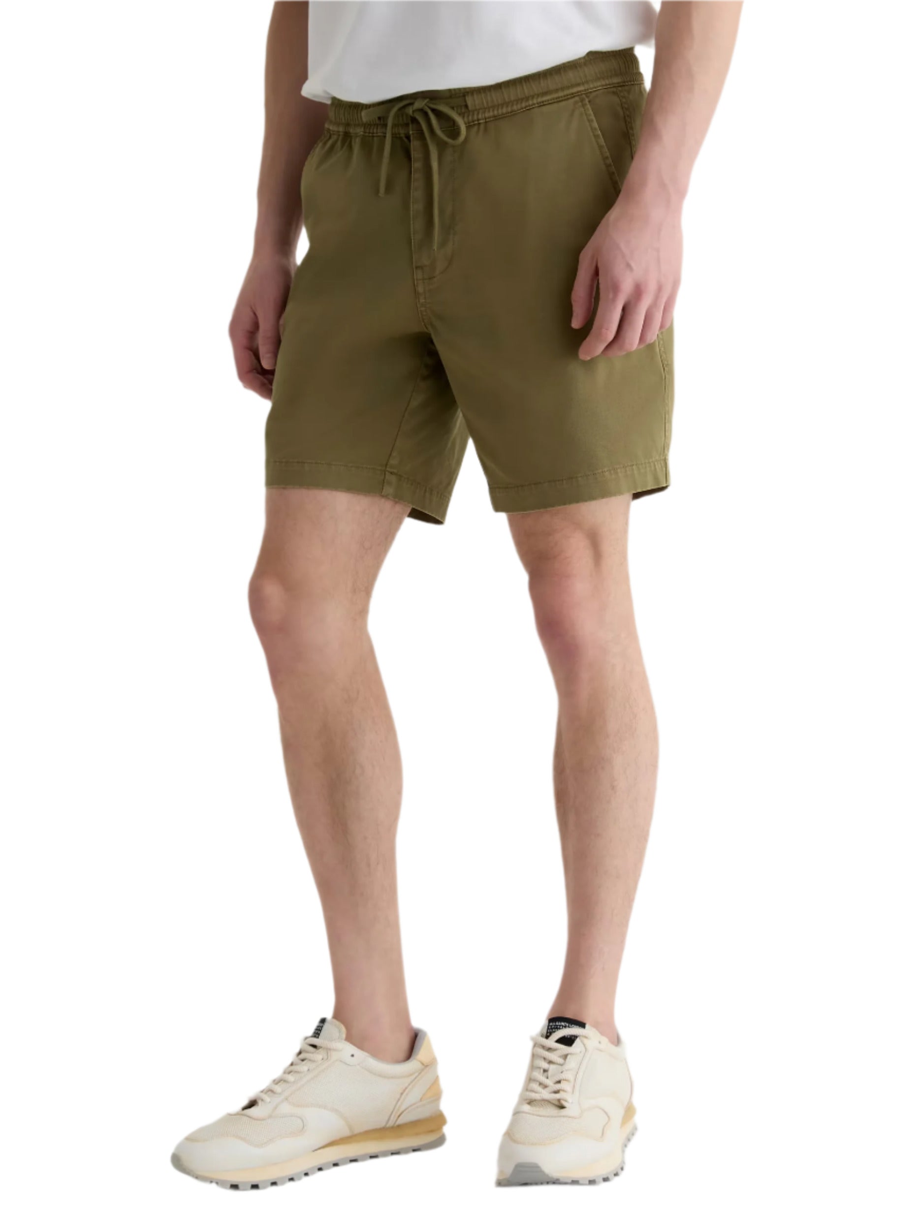 Someone wearing the AG Jeans Oliver Short, made from a breathable twill blend with an adjustable drawstring waist, pairs it with a white t-shirt and beige sneakers while standing against a plain background.