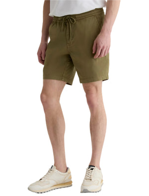 Someone wearing the AG Jeans Oliver Short, made from a breathable twill blend with an adjustable drawstring waist, pairs it with a white t-shirt and beige sneakers while standing against a plain background.