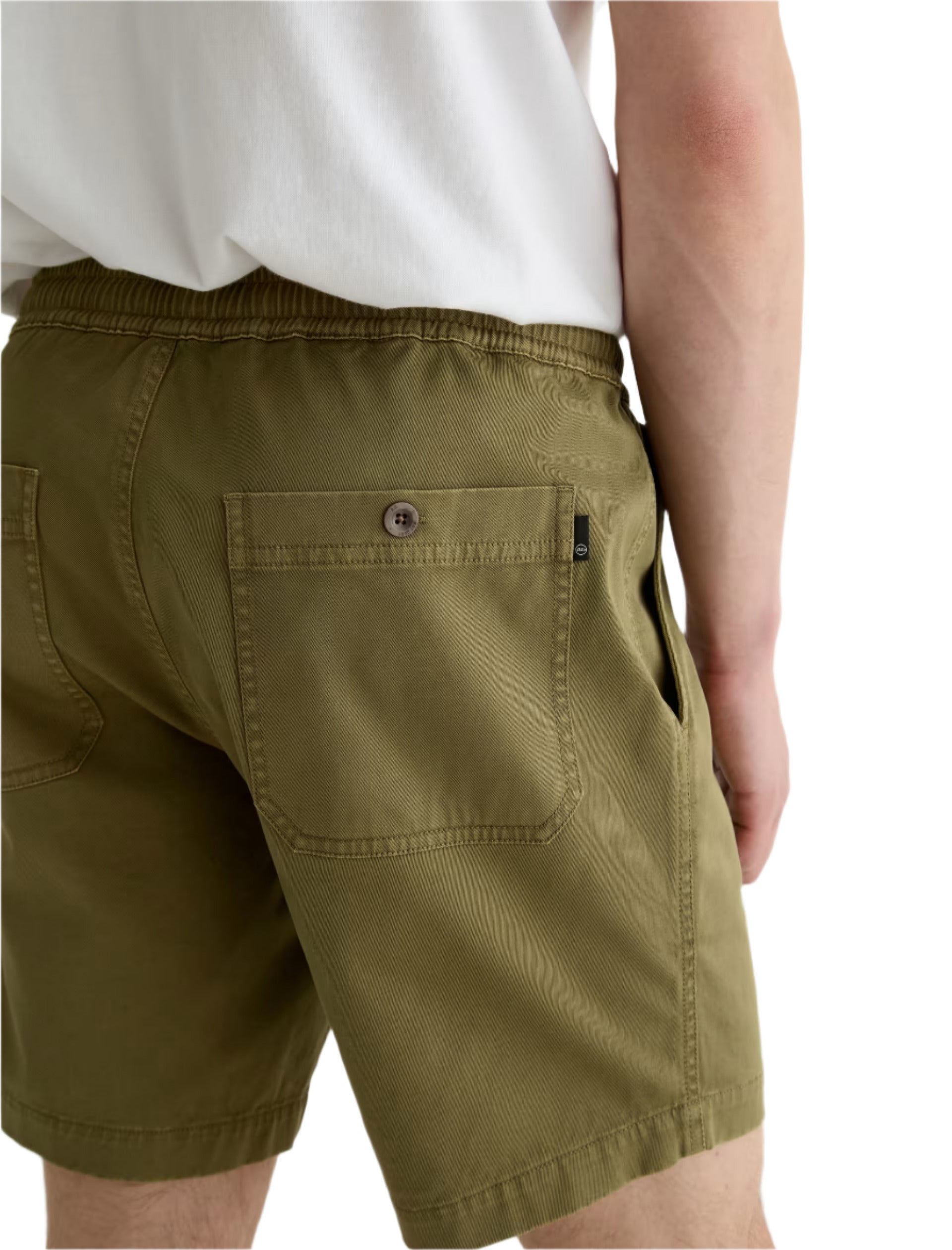 A person is shown from the back wearing AG Jeans’ Oliver Short in olive green, featuring a breathable twill blend, adjustable drawstring waist, and detailed back pockets.