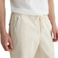 A person wearing a white T-shirt and AG Jeans Tate Drawstring Pant in khaki stands with hands relaxed at their sides.