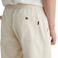 A person wearing the Tate Drawstring Pant by AG Jeans, made from light beige twill linen with patch pockets and an elastic waistband, shown from the back and cropped at the waist.