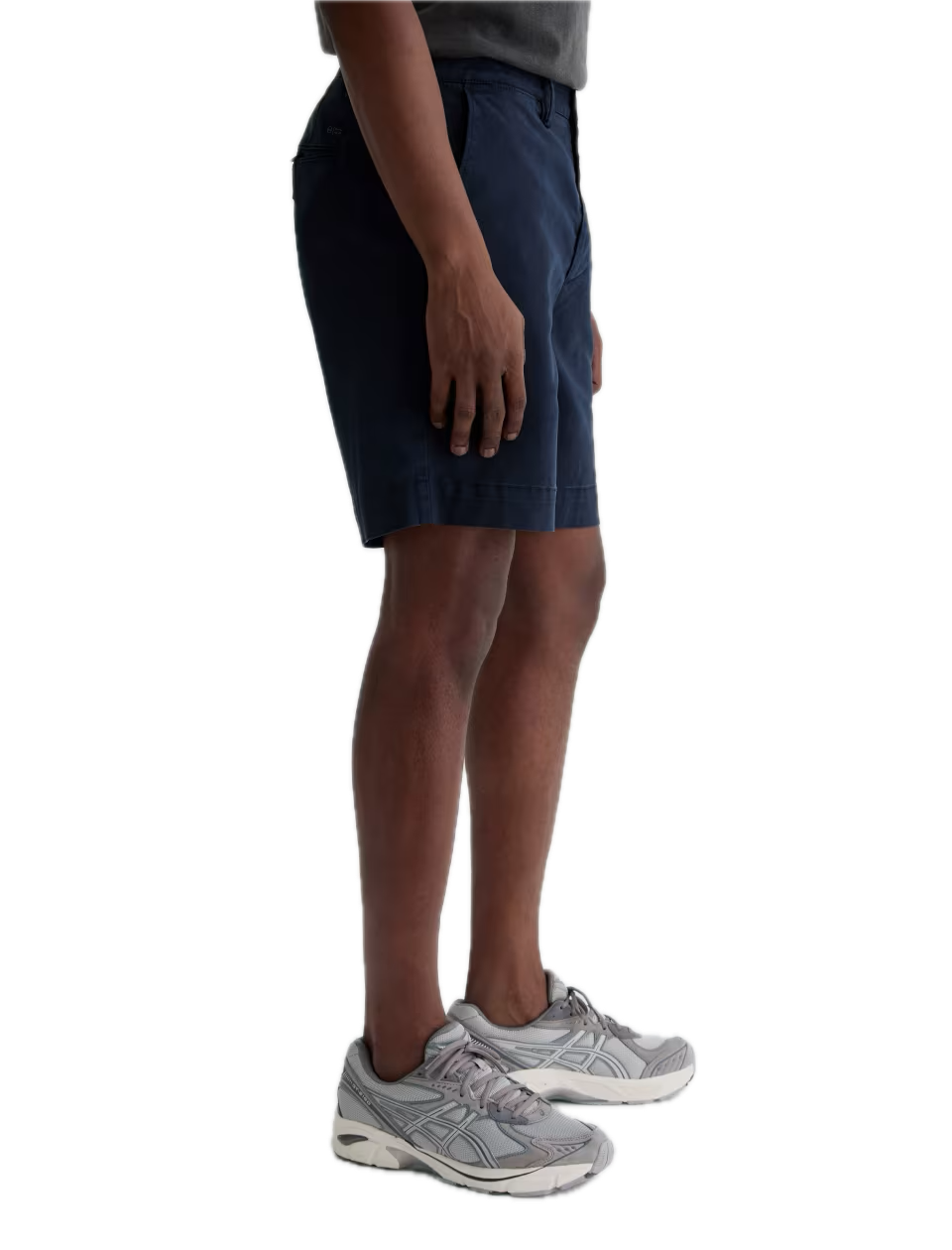 A person wearing a gray t-shirt, navy blue Archie Short from AG Jeans—crafted from premium Sorrento Stretch Twill Italian fabric—and gray sneakers stands against a plain white background.