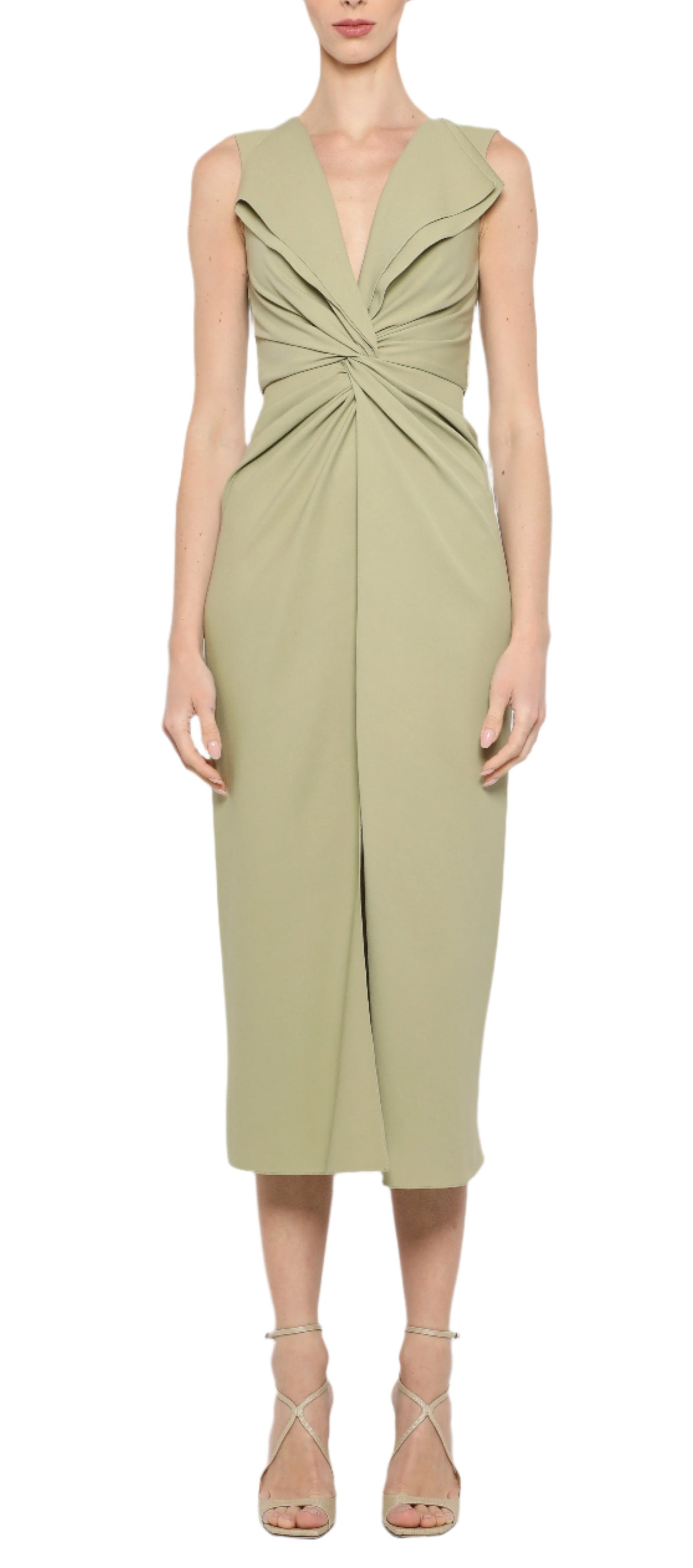 A woman in the sophisticated Prabal Gurung Lily Twist Front Dress, showcasing a sleeveless, knee-length style in light olive green with a V-neck and front knot detail, stands against a white background. Her outfit is perfectly completed with strappy high heels.